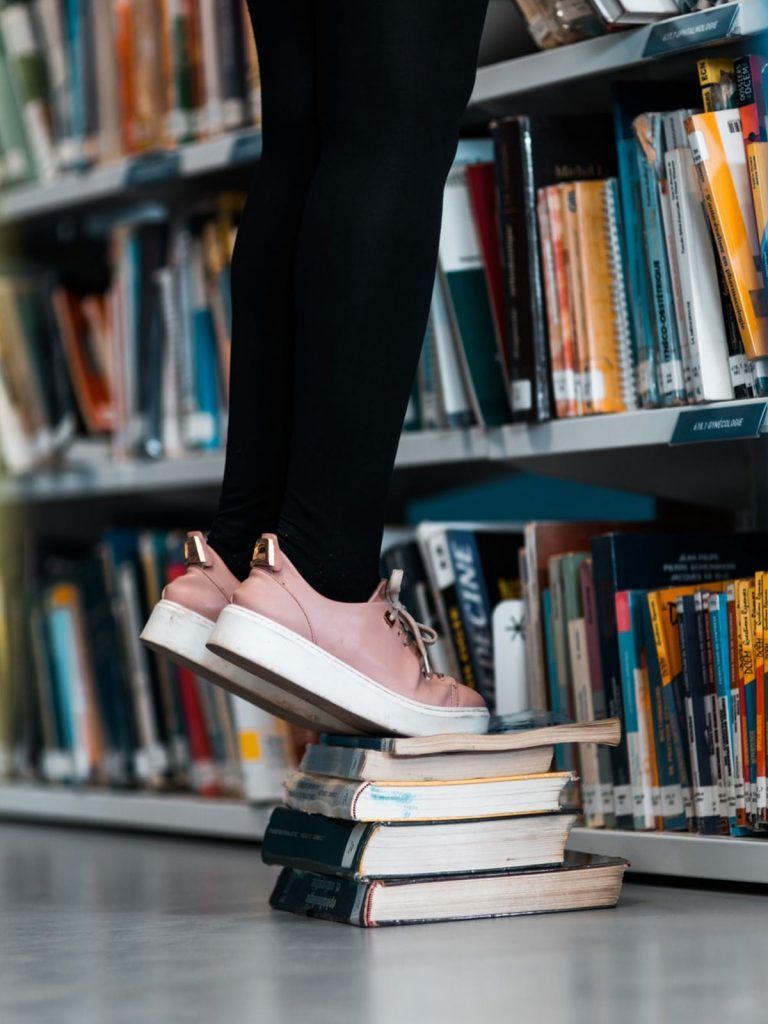 A person standing on books in library only showing lower legs and floor