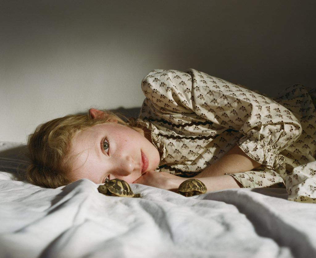A photo of a girl lying on a bed looking into the camera